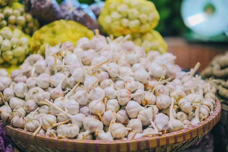 A wide basket heaped with fresh garlic on a market table