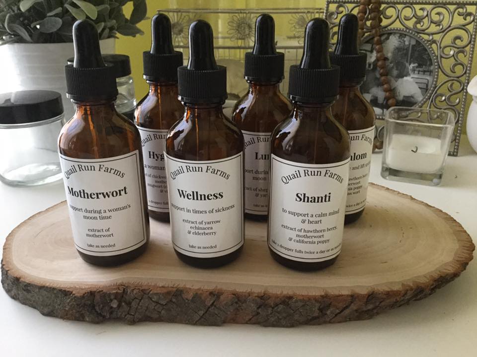 Hand-labelled herbal tincture bottles from a local farm, lined up on a wood slice