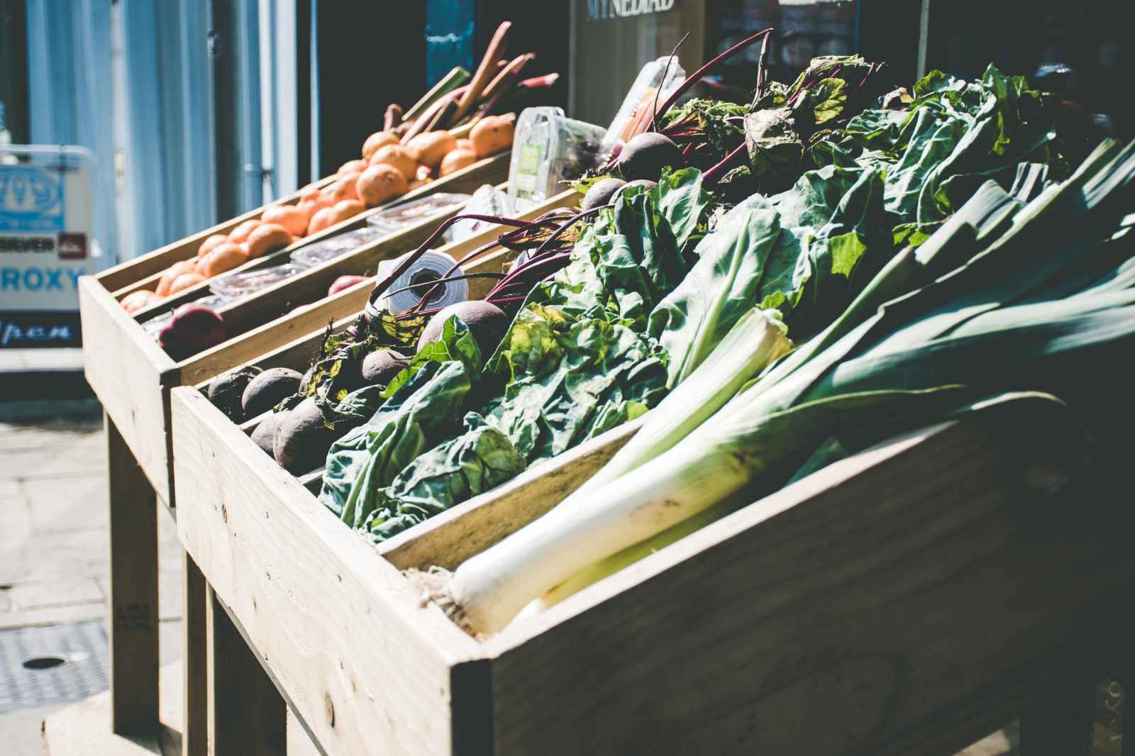 Crates of leeks, chard, beets and citrus on a market table